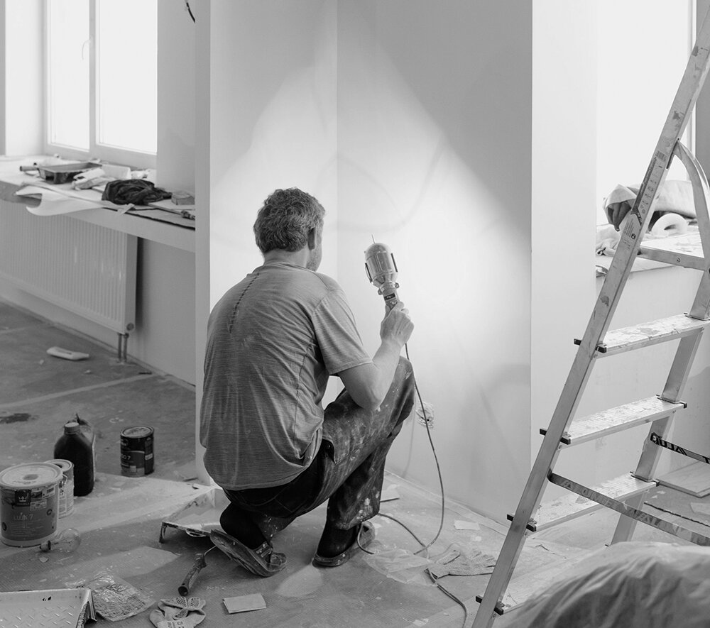 Man working in house doing plastering with lamp drying the wall